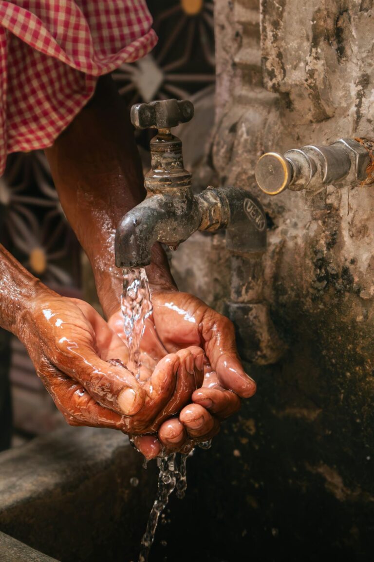 Close-up of hands gathering water from a faucet in Jalandhar, India, illustrating daily life and resourcefulness.